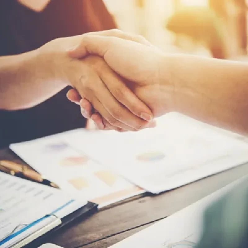 primer-plano-de-dos-personas-de-negocios-dandose-la-mano-mientras-esta-sentado-en-el-lugar-de-trabajop
